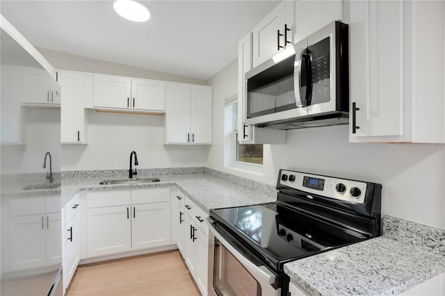 kitchen with white cabinetry, sink, stainless steel appliances, and light hardwood / wood-style floors