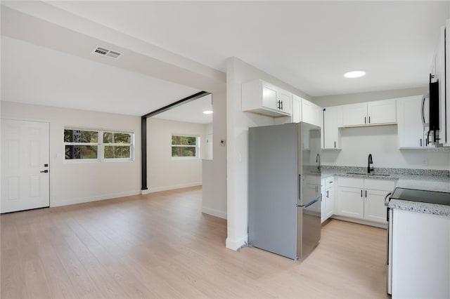 kitchen with white cabinetry, sink, light hardwood / wood-style floors, stainless steel appliances, and light stone countertops