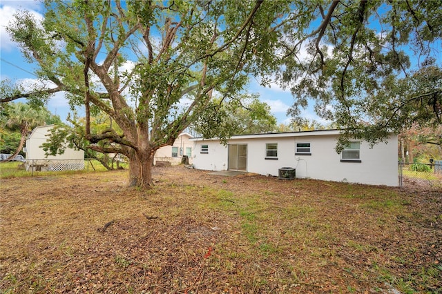 back of property with central AC unit and a lawn