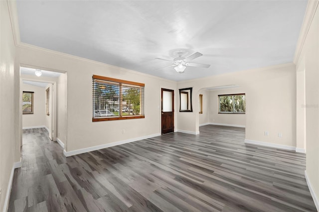 unfurnished living room featuring crown molding, ceiling fan, dark hardwood / wood-style flooring, and a wealth of natural light