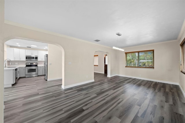 unfurnished living room featuring ornamental molding, sink, and dark hardwood / wood-style floors