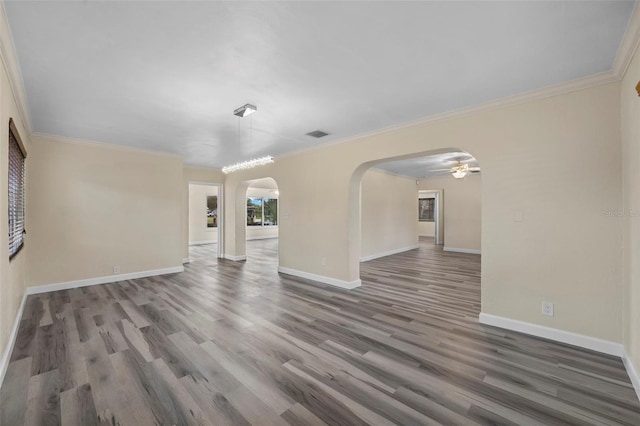 unfurnished living room featuring dark hardwood / wood-style flooring, ornamental molding, and ceiling fan