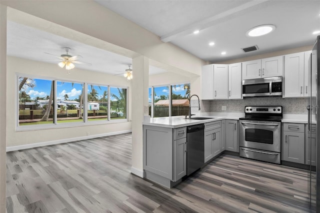 kitchen featuring sink, gray cabinetry, wood-type flooring, stainless steel appliances, and decorative backsplash