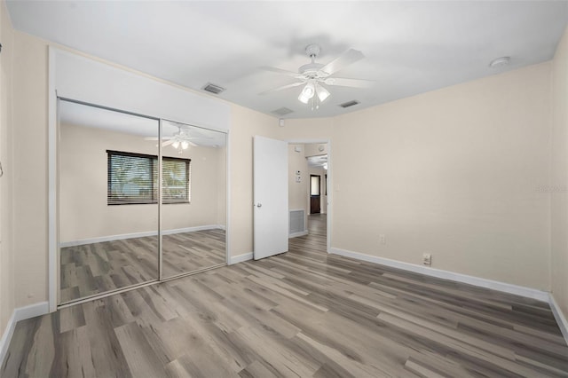 unfurnished bedroom featuring hardwood / wood-style flooring, ceiling fan, and a closet