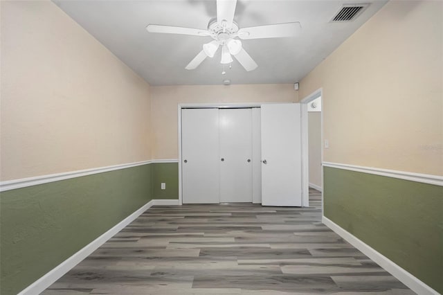 unfurnished bedroom with hardwood / wood-style floors, ceiling fan, and a closet