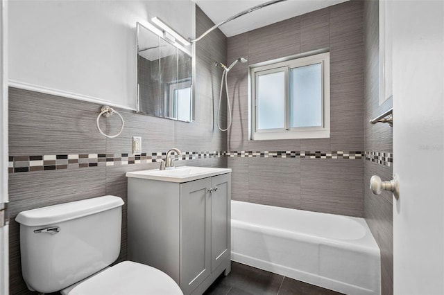 full bathroom featuring tile walls, tiled shower / bath combo, vanity, toilet, and tile patterned floors