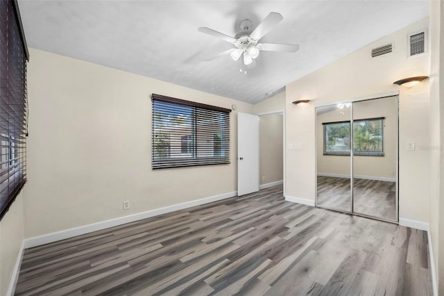 unfurnished bedroom with lofted ceiling, hardwood / wood-style floors, a closet, and ceiling fan