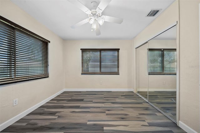 spare room with dark hardwood / wood-style flooring, ceiling fan, and a healthy amount of sunlight