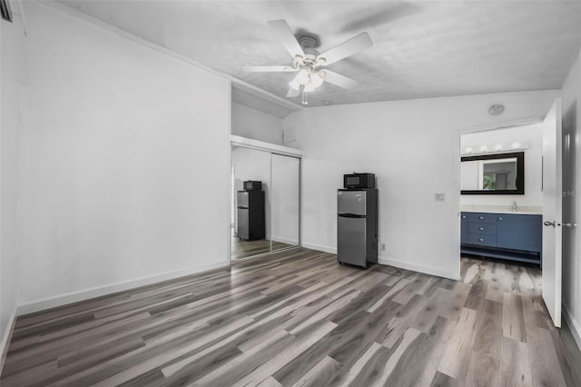 unfurnished living room with ceiling fan, sink, and dark hardwood / wood-style flooring