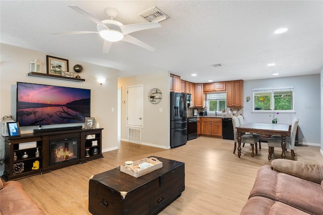 living room featuring ceiling fan and light hardwood / wood-style flooring