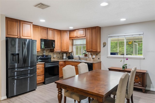 kitchen featuring sink, range with electric stovetop, refrigerator with ice dispenser, a healthy amount of sunlight, and backsplash