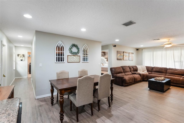 dining space featuring ceiling fan, a textured ceiling, and light wood-type flooring