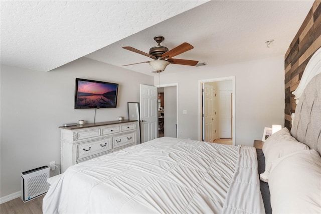 bedroom with ceiling fan, light hardwood / wood-style floors, and a textured ceiling