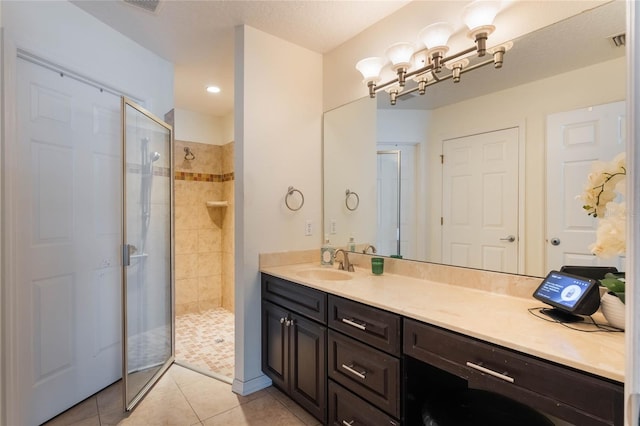 bathroom featuring tile patterned flooring, vanity, and a tile shower