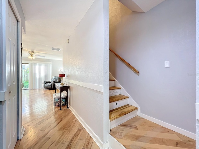 staircase featuring ceiling fan and wood-type flooring