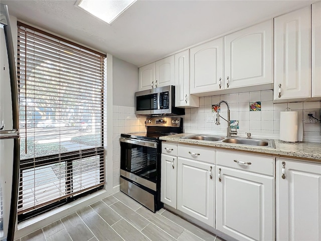 kitchen featuring stainless steel appliances, white cabinetry, sink, and tasteful backsplash