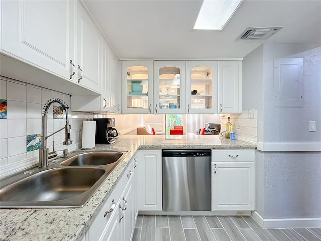 kitchen with sink, white cabinets, backsplash, stainless steel dishwasher, and electric panel