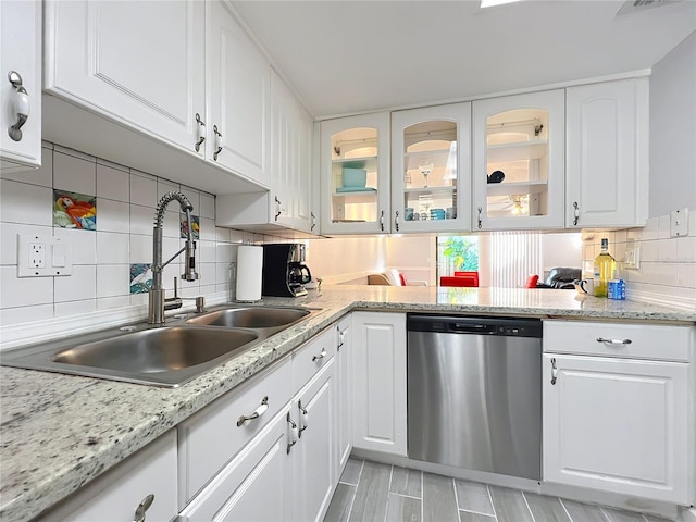 kitchen with white cabinetry, stainless steel dishwasher, sink, and backsplash