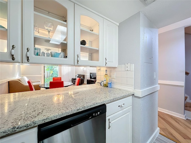 kitchen with hardwood / wood-style flooring, white cabinetry, backsplash, light stone counters, and stainless steel dishwasher