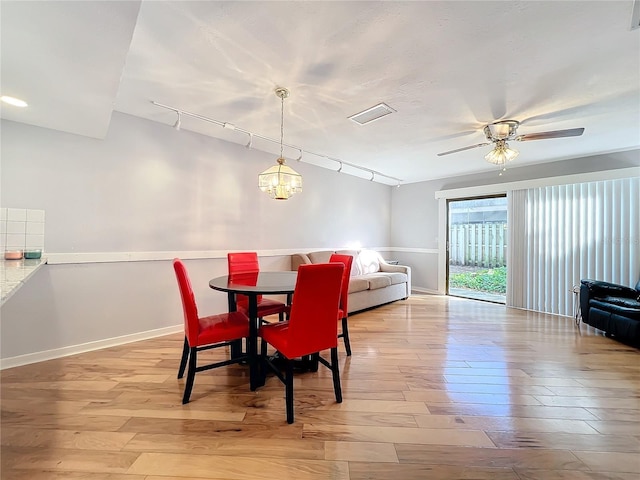 dining area featuring ceiling fan with notable chandelier, rail lighting, and light hardwood / wood-style floors