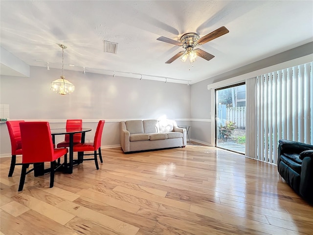 dining room featuring ceiling fan with notable chandelier and light wood-type flooring