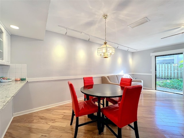 dining space with a notable chandelier, rail lighting, and light wood-type flooring