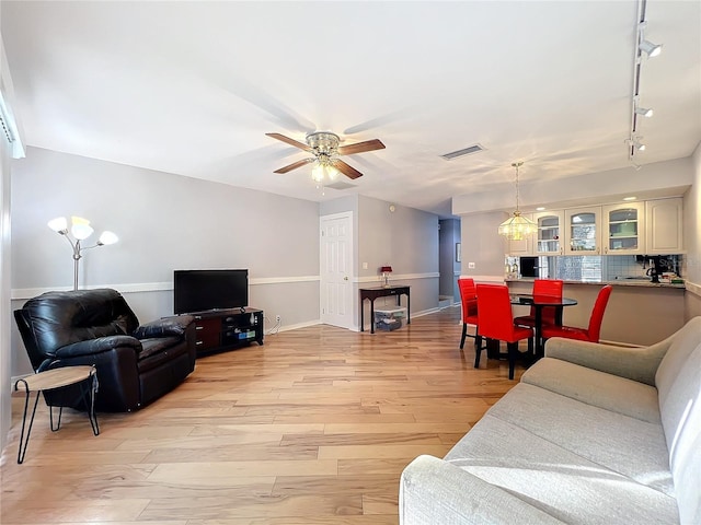 living room with ceiling fan, track lighting, and light hardwood / wood-style flooring