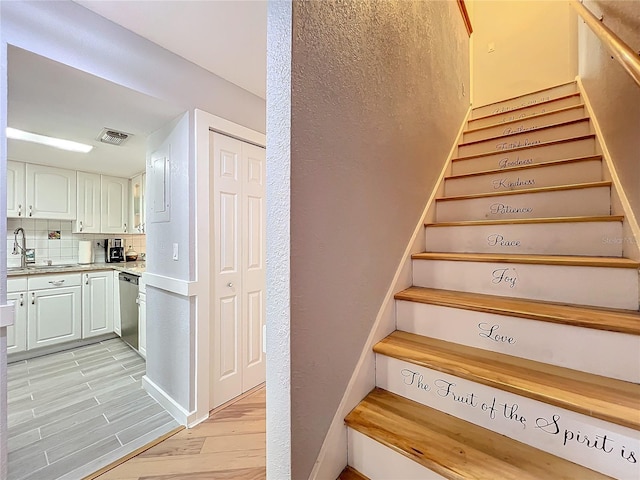 staircase featuring sink and hardwood / wood-style floors