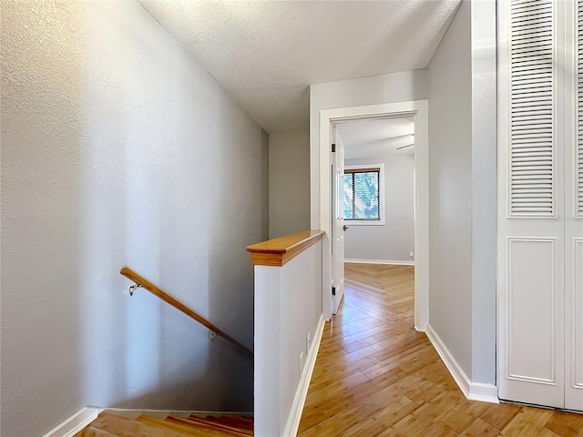 hall with a textured ceiling and light wood-type flooring