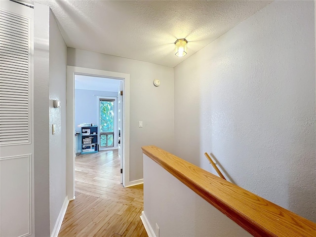 hallway featuring a textured ceiling and light wood-type flooring