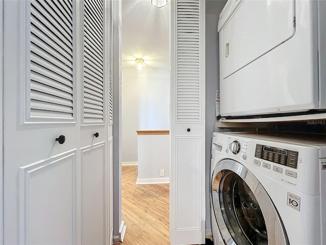 washroom with stacked washer / dryer and light hardwood / wood-style flooring