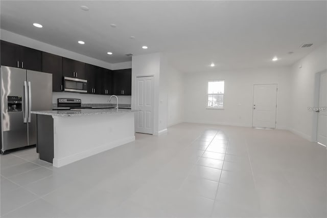 kitchen with stainless steel appliances, sink, a center island with sink, and light tile patterned floors