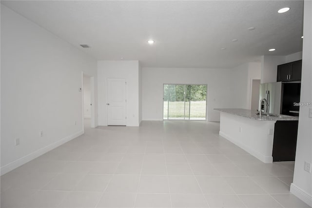 interior space featuring open floor plan, baseboards, visible vents, recessed lighting, and stainless steel fridge with ice dispenser