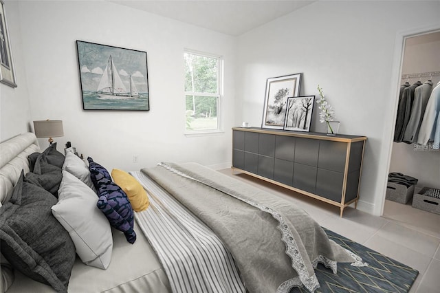 tiled bedroom with a spacious closet, baseboards, and a closet