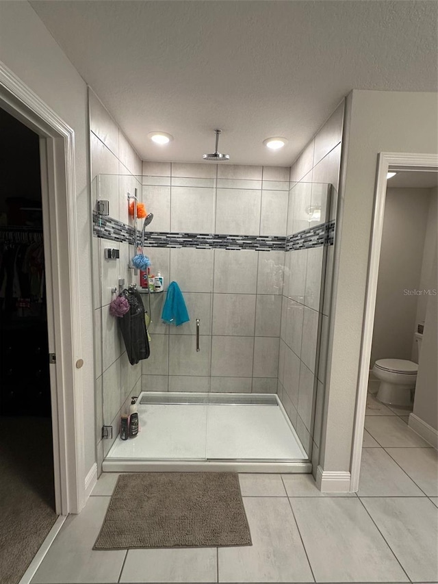 bathroom with tile patterned floors, toilet, a shower with door, and a textured ceiling