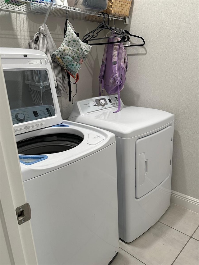 clothes washing area featuring washing machine and clothes dryer and light tile patterned flooring