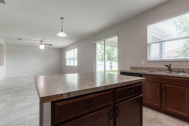 kitchen with sink, light tile patterned floors, ceiling fan, hanging light fixtures, and a kitchen island