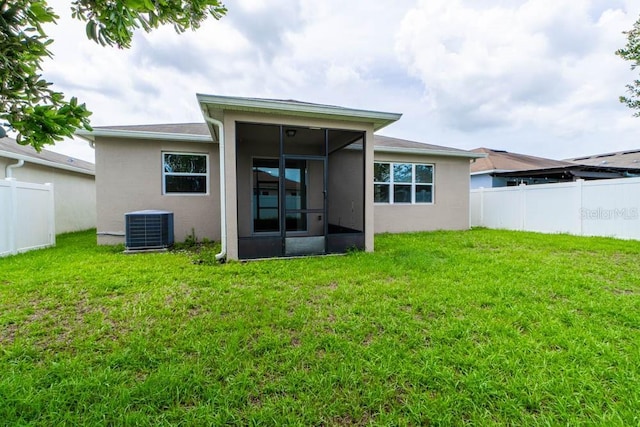 rear view of property featuring a yard, central AC, and a sunroom