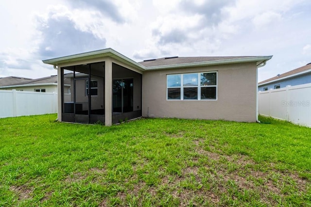 rear view of house with a sunroom and a lawn