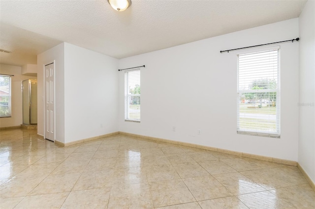 tiled empty room with a textured ceiling