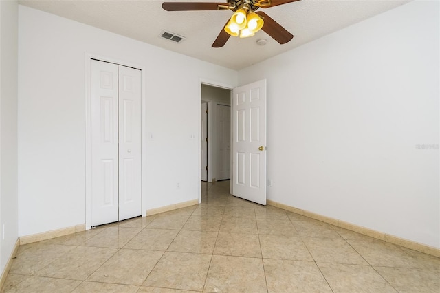 unfurnished bedroom featuring light tile patterned floors, a textured ceiling, ceiling fan, and a closet