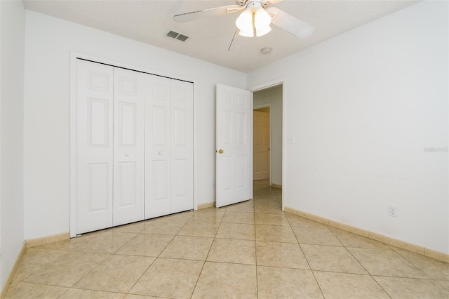 unfurnished bedroom with light tile patterned floors, a closet, and ceiling fan