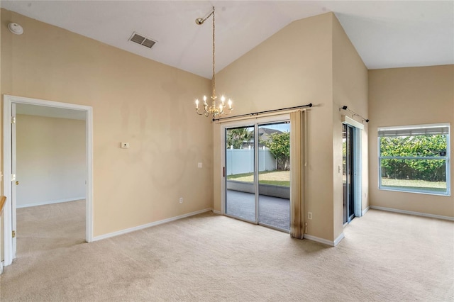 spare room featuring a notable chandelier, light carpet, and a wealth of natural light