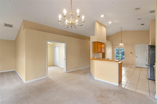 kitchen featuring lofted ceiling, stainless steel fridge, hanging light fixtures, kitchen peninsula, and light carpet