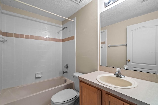 full bathroom with tiled shower / bath combo, vanity, a textured ceiling, and toilet