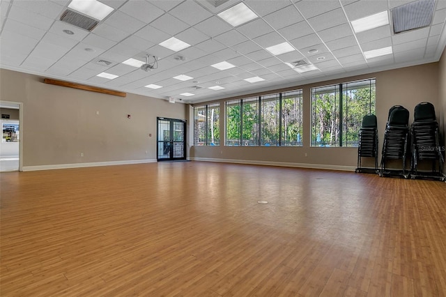 workout room featuring a paneled ceiling and light wood-type flooring