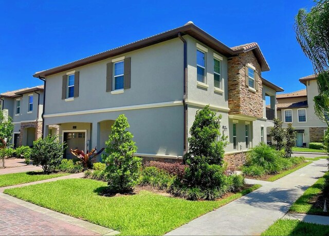 view of front of house with stone siding, a front yard, and stucco siding