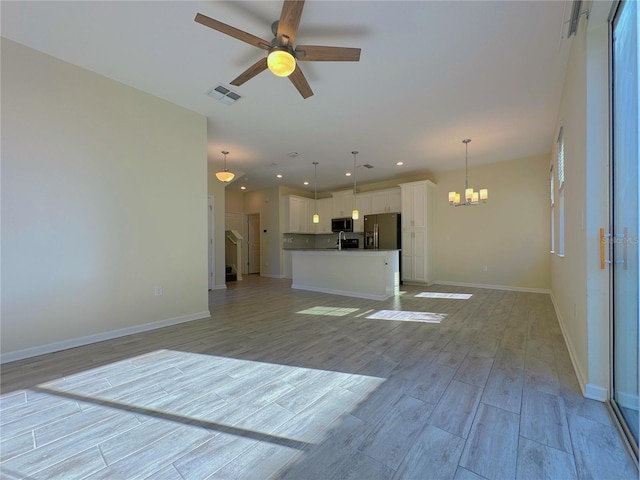 unfurnished living room with recessed lighting, visible vents, light wood-style floors, baseboards, and ceiling fan with notable chandelier