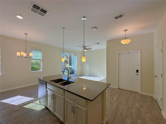 kitchen featuring dishwasher, a sink, visible vents, and light wood-style floors