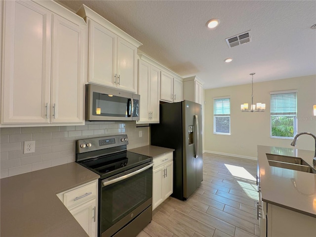 kitchen with visible vents, white cabinets, decorative backsplash, stainless steel appliances, and a sink